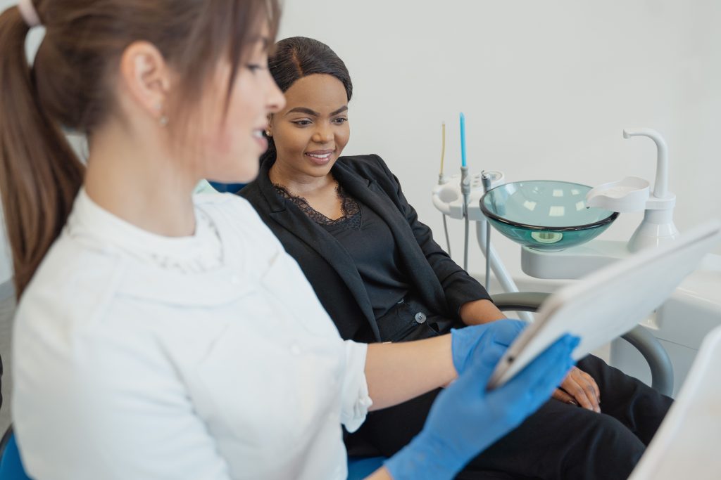 Healthcare professional discussing dental treatment with patient using a tablet device in a modern clinic setting.